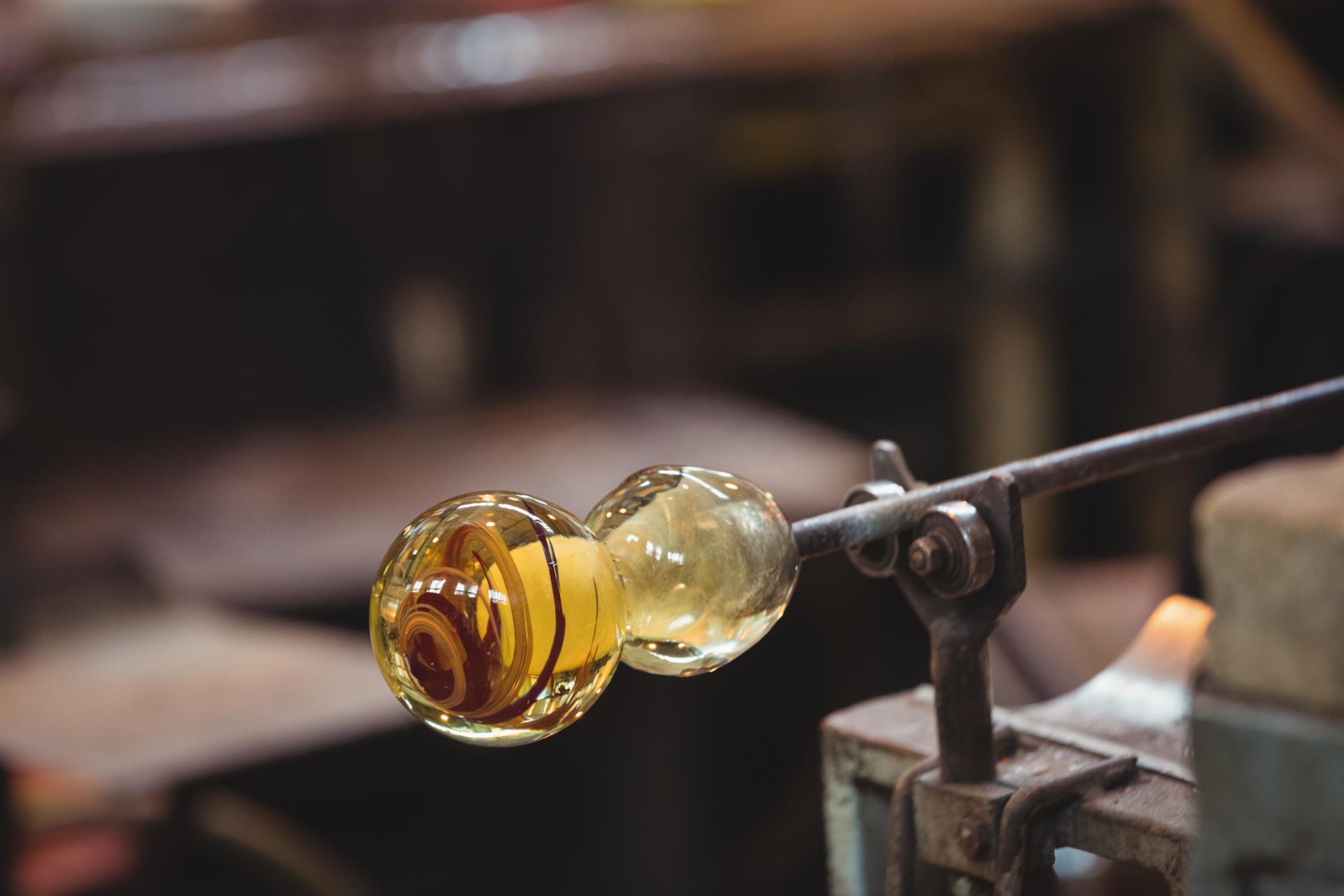 Murano glassblower shaping glass on a blowpipe
